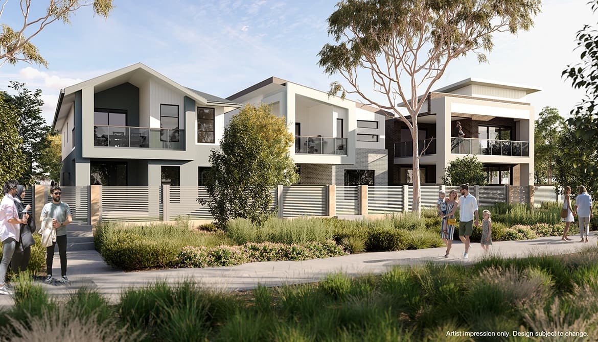 Modern two-story houses with large balconies and glass railings, surrounded by greenery and trees. People are walking and socializing along a landscaped path in front of the homes under a blue sky.