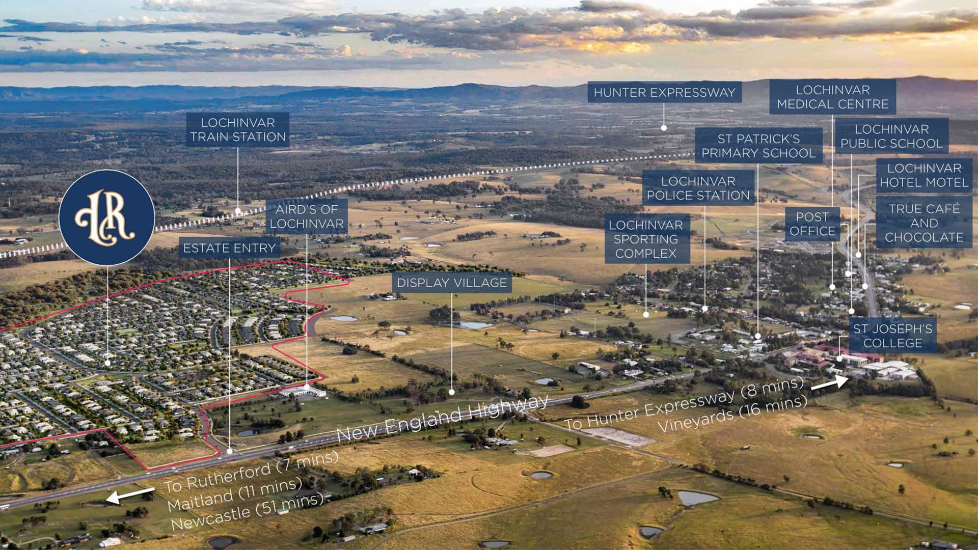 Aerial view of a rural town with annotated labels marking locations like schools, train station, medical center, hotel, and main roads. A residential estate is outlined in the foreground with nearby amenities indicated.