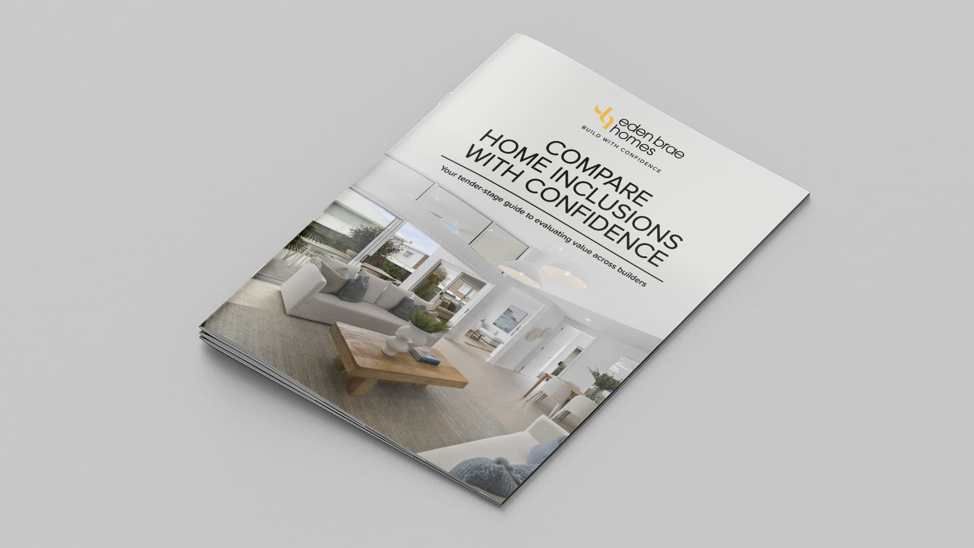 A brochure with the title “Compare Home Inclusions With Confidence” lies on a gray surface, featuring a modern living room interior on the cover and the logo for Beachwood Homes at the top.