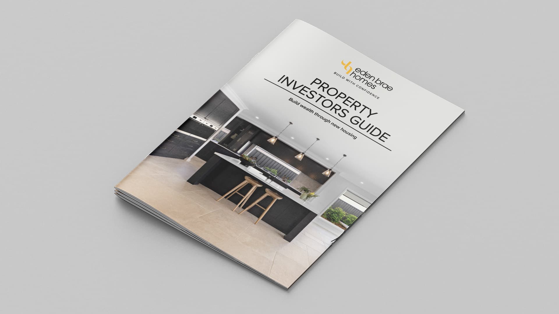 A property investors guide booklet features a modern kitchen on the cover, with sleek black cabinets, a large island, and barstools. The booklet is titled “Property Investors Guide” by Beachwood Homes.