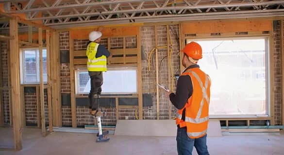 A man standing on a ladder in a construction site.